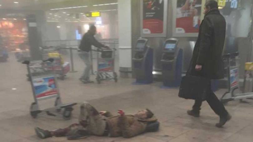 Homem atravessa saguão ao lado de um ferido no aeroporto de Bruxelas