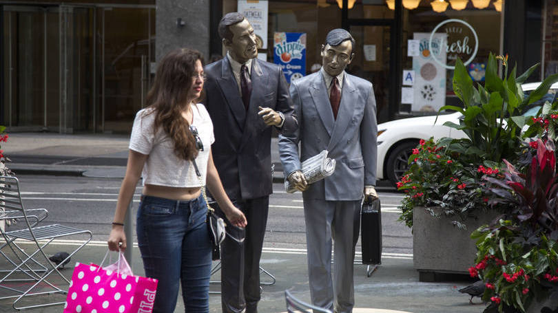 Jovem caminha com sacola ao lado de uma escultura de Seward Johnson em Nova York, nos Estados Unidos