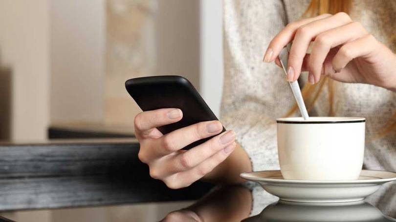 Mulher segura smartphone durante o café