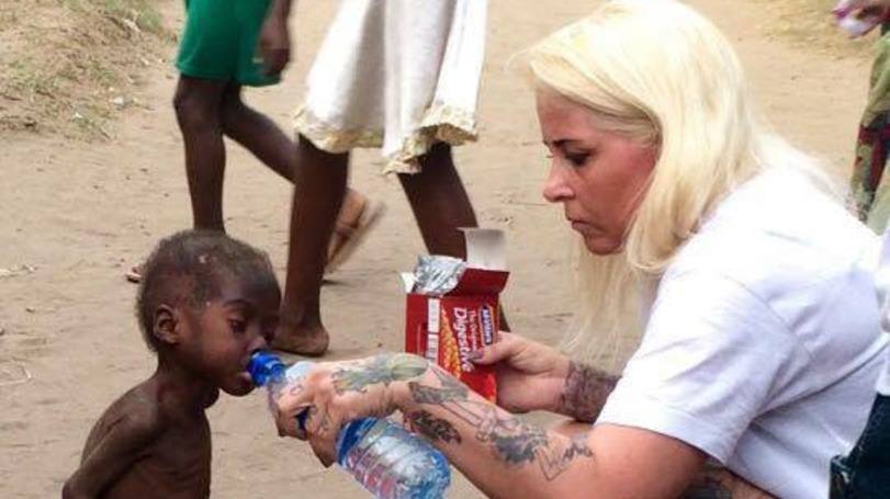 Voluntária de ONG alimentando uma criança de 2 anos rejeitada pela sua comunidade na Nigéria