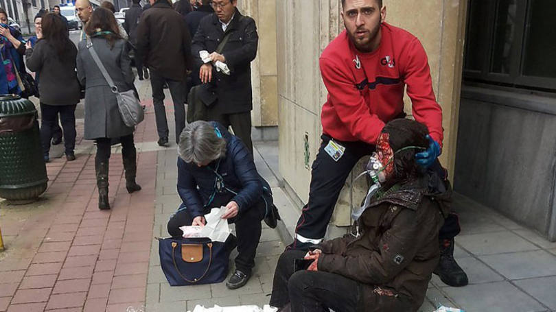 Segurança ajuda mulher ferida em explosões da estação de Maalbeek, em Bruxelas: 20 mortes seriam decorrentes da explosão em um trem do metrô e as outras 14 de explosões em um aeroporto