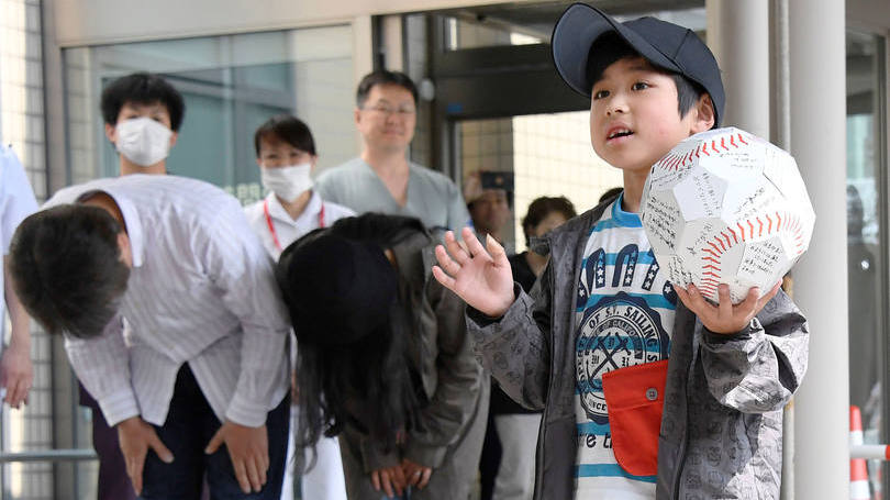 Yamato Tanooka: sorridente, ele exibia uma grande bola de beisebol de papel repleta de assinaturas, um provável presente da equipe médica