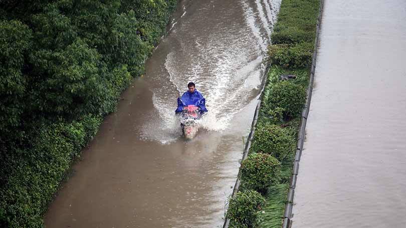 Um motociclista passa, solitário, por uma rua inundada em Changzhou, província de Jiangsu, China, em 2 de julho
