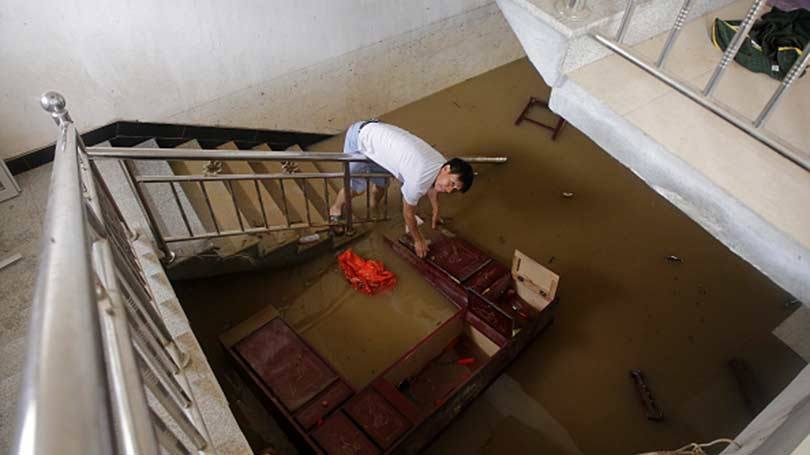 Morador procura pertences em uma casa inundada na província central de Hubei da China, em 03 de julho.