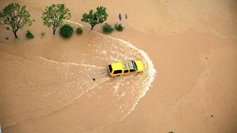 Um veículo tenta atravessar uma rua inundada em Rongjiang, Província de Guizhou, na China, em 2 de julho.  