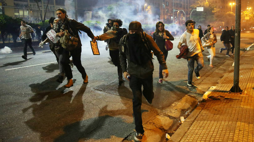Brasil  Manifestantes correm das bombas de gás lacrimogênio usadas pela polícia que tentava dispersar uma multidão durante um ato contra o impeachment de Dilma Rousseff em São Paulo. Em um dos atos registrados na cidade, uma estudante perdeu a visão do olho esquerdo após ter sido atingida por estilhaços dessas bombas.  É o terceiro caso em que pessoas perderam a visão em decorrência da ação de repressão policial em manifestações na capital.