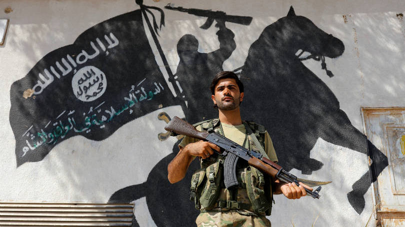 Síria  Membro do Exército Livre da Síria, grupo rebelde apoiado pela Turquia, é fotografado em frente a um mural do grupo terrorista Estado Islâmico (EI) durante guarda em prédio na cidade de Jarablus. Nesta semana, foi anunciada a morte do porta-voz do EI, cuja autoria é agora disputada pelos Estados Unidos e pela Rússia.