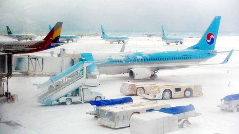 Neve encobre aviões no aeroporto internacional de Jeju, no Coreia do Sul: no sábado, 296 voos foram cancelados e 122 foram atrasados